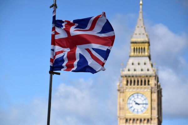 Close-up of UK flag with Big Ben in the background, representing UK economy, economic uncertainty and rising inflation in the UK.