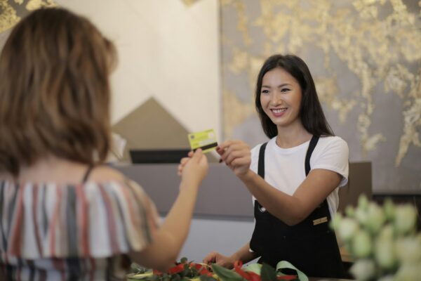 Woman paying with best cashback credit cards at store checkout using contactless payment