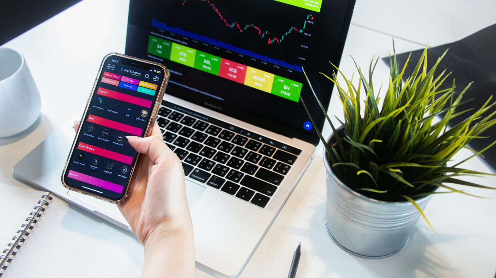 Person checking dividend stocks portfolio on laptop and smartphone for passive income investing