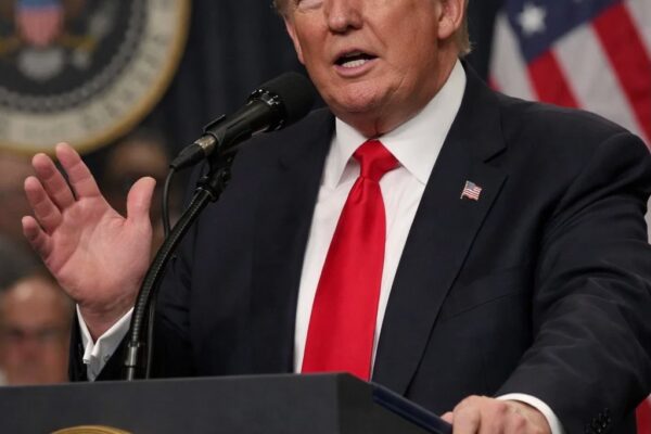 President Donald Trump speaks at a podium, highlighting his criticism of mail-in voting just days after casting a mail-in ballot, as reported by The Guardian.