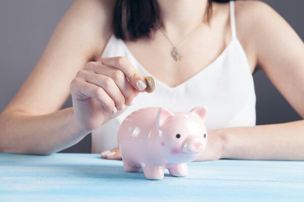 Adding a coin to a Piggy bank representing an emergency fund – start an emergency fund 2026 on a tight budget